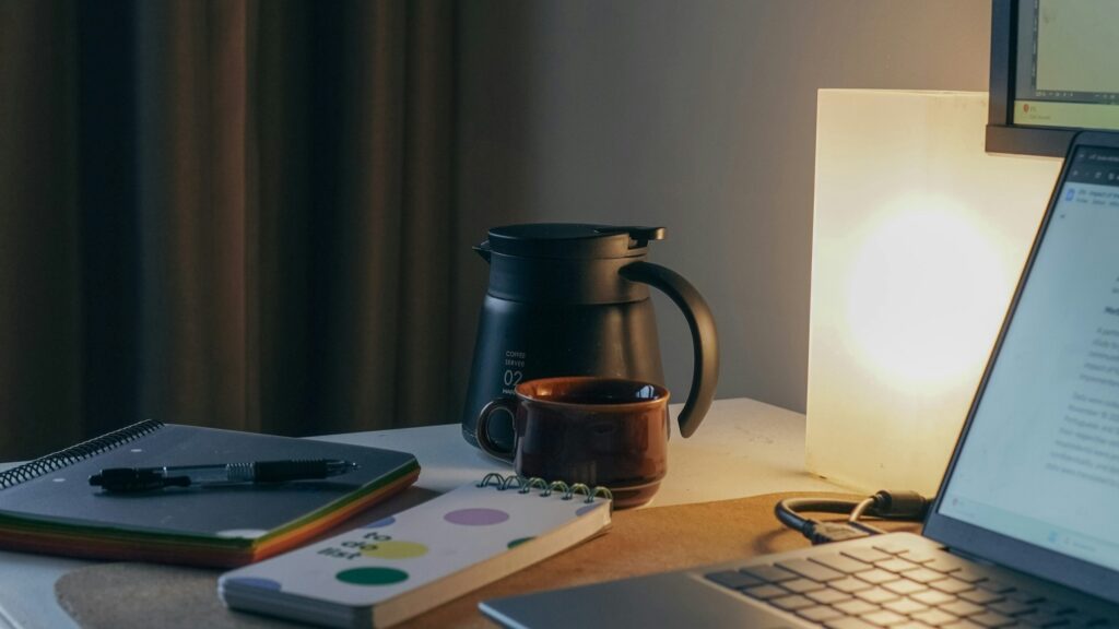 Un bloc-note, une théière et un ordinateur portable posés sur un bureau prêt pour apprendre l'informatique.